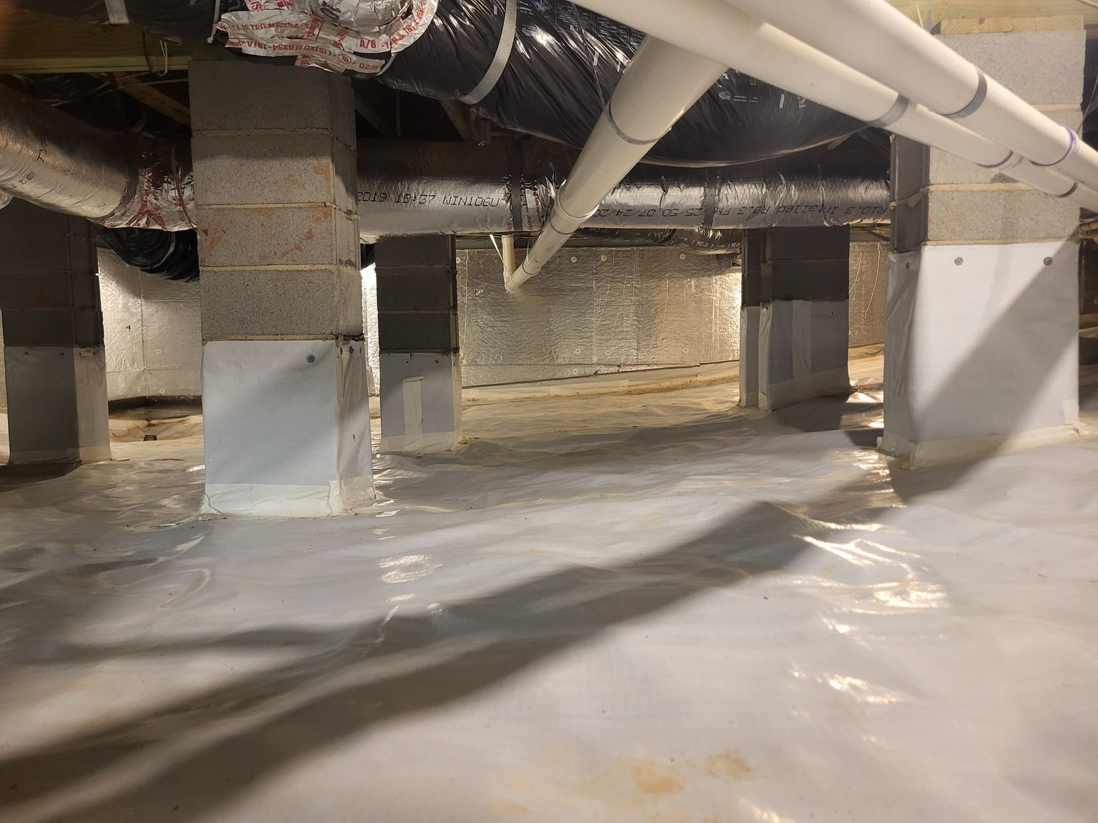 New white vapor barrier membrane covering a crawl space floor